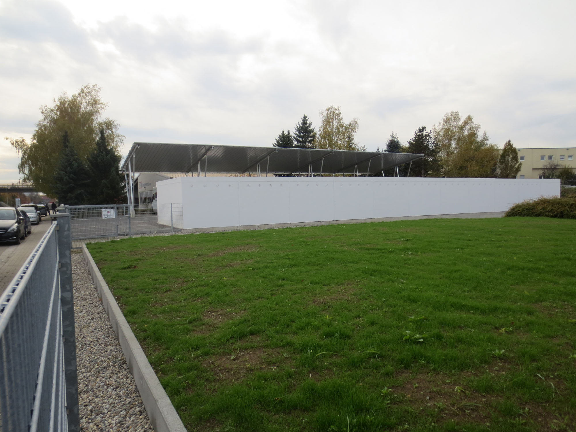 Weiße Garagenanlage mit überdachten Stellplätzen und gepflegter Grünfläche
