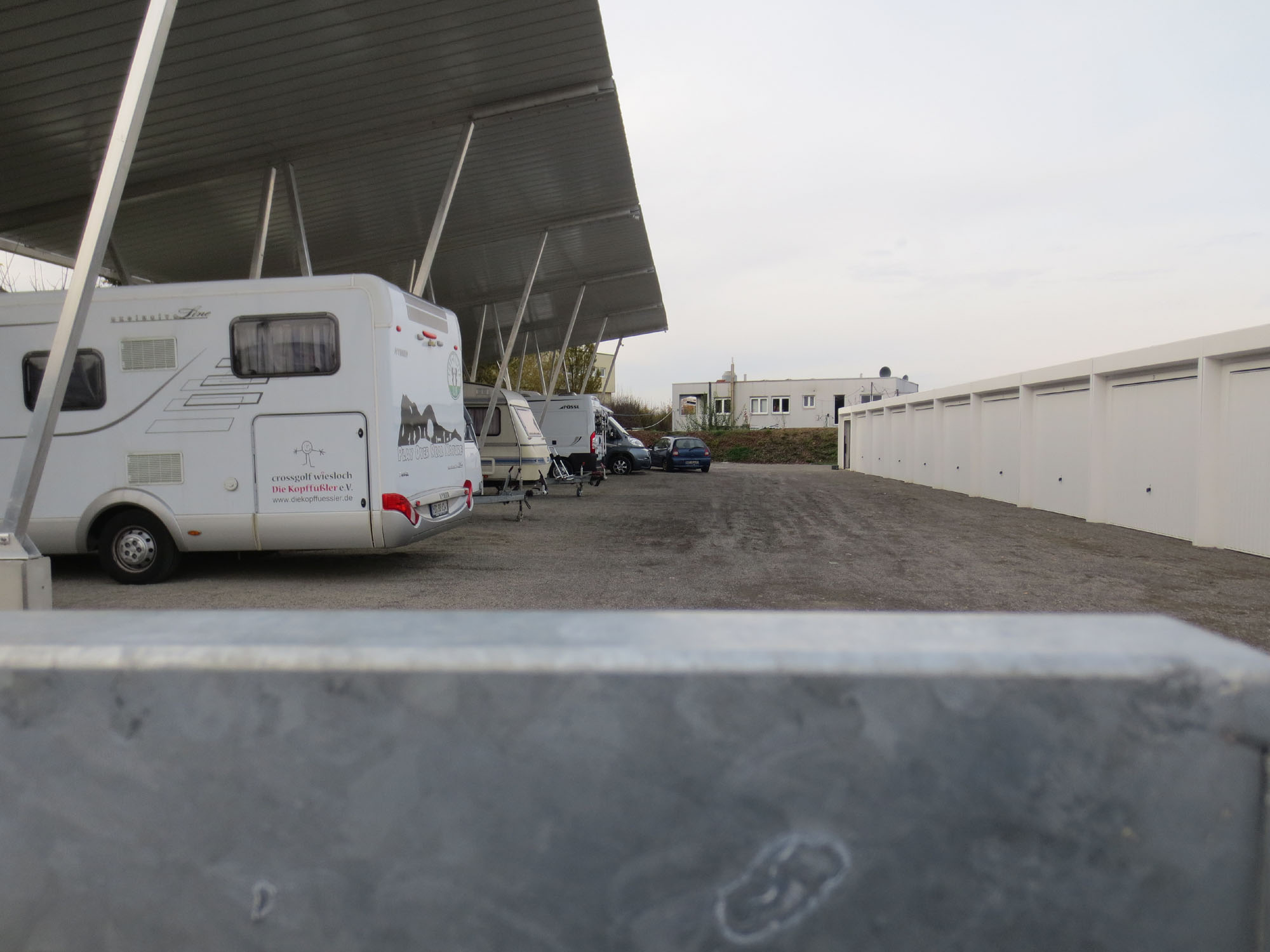 Reihe abgestellter Wohnmobile unter dem Carport-Dach